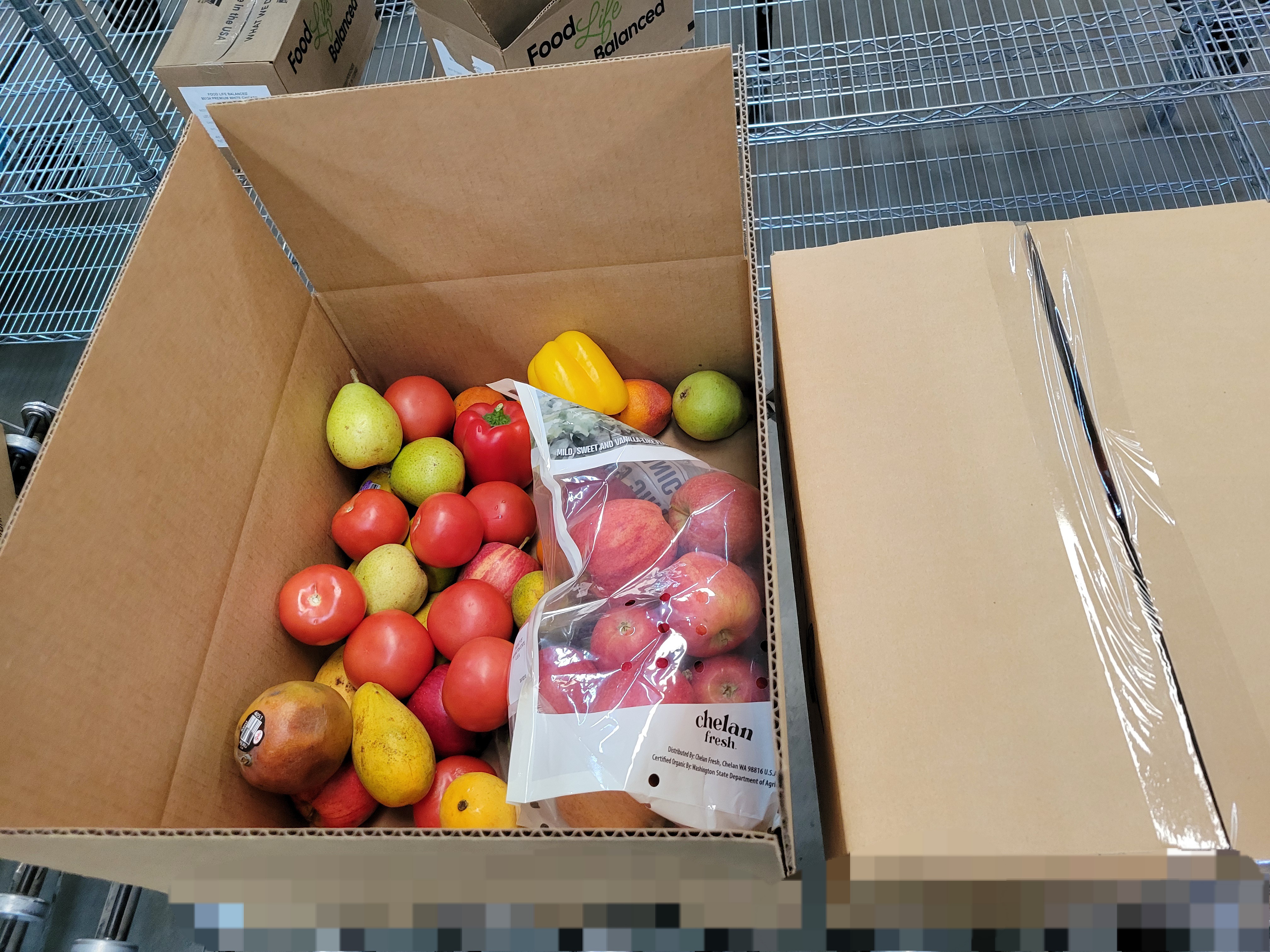 Various produce in cardboard box next to a taped box.
